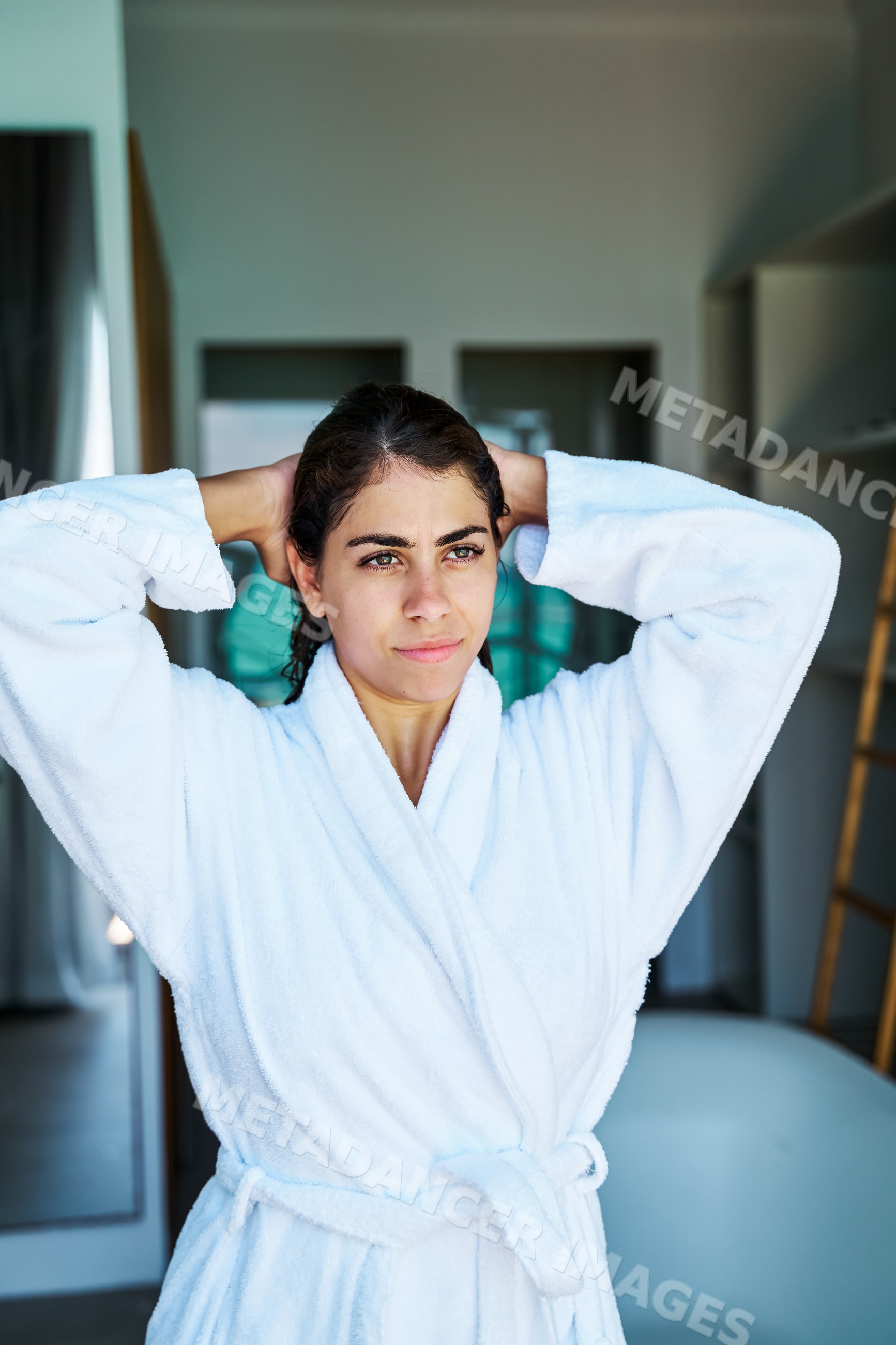 A woman in a white bathrobe standing indoors in a bathroom
