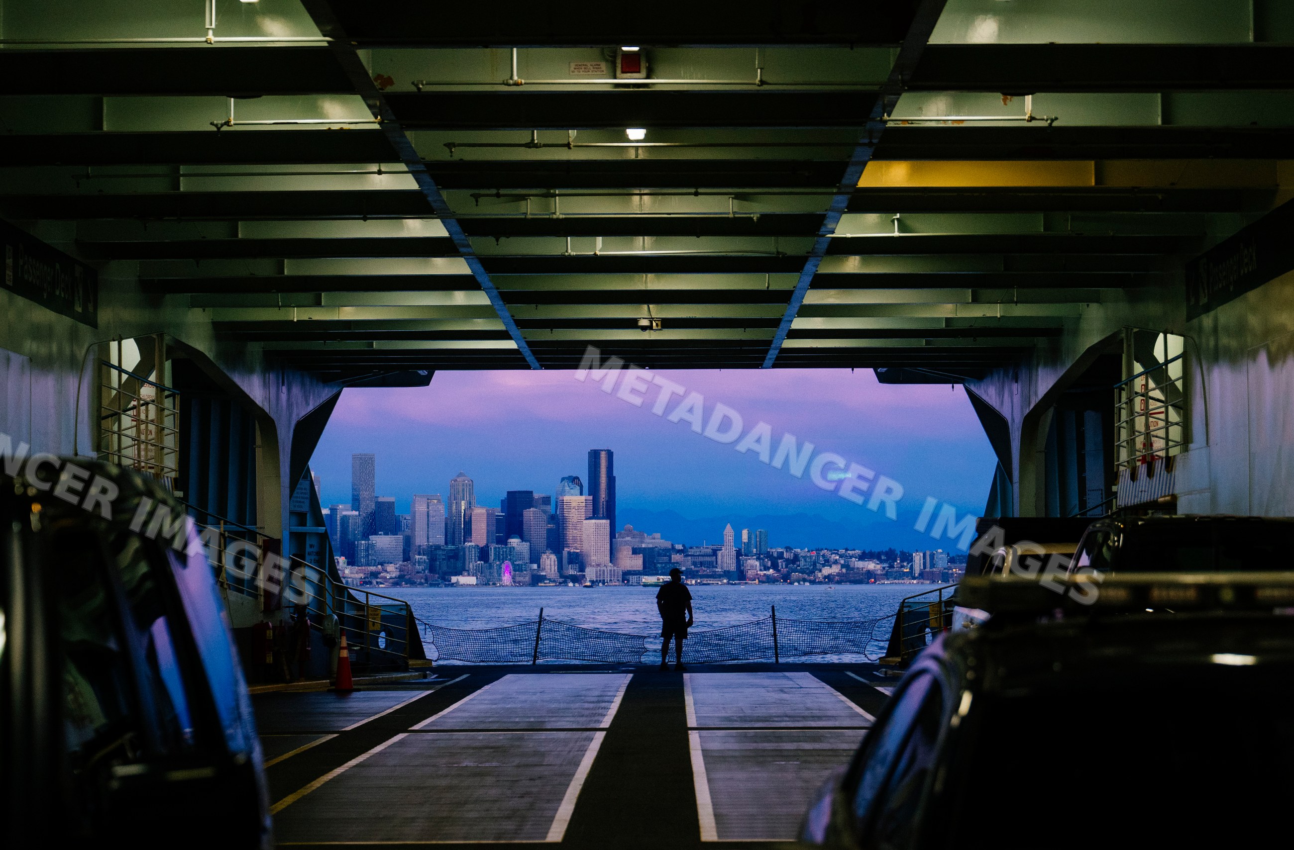 White person on ferry deck viewing city skyline at twilight