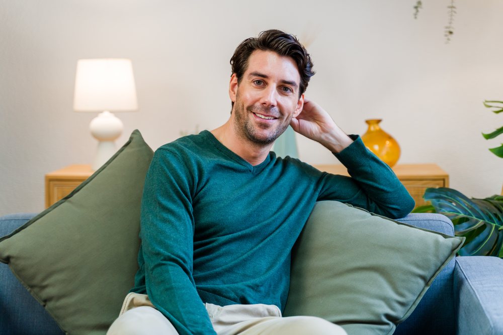 White man sitting on sofa smiling