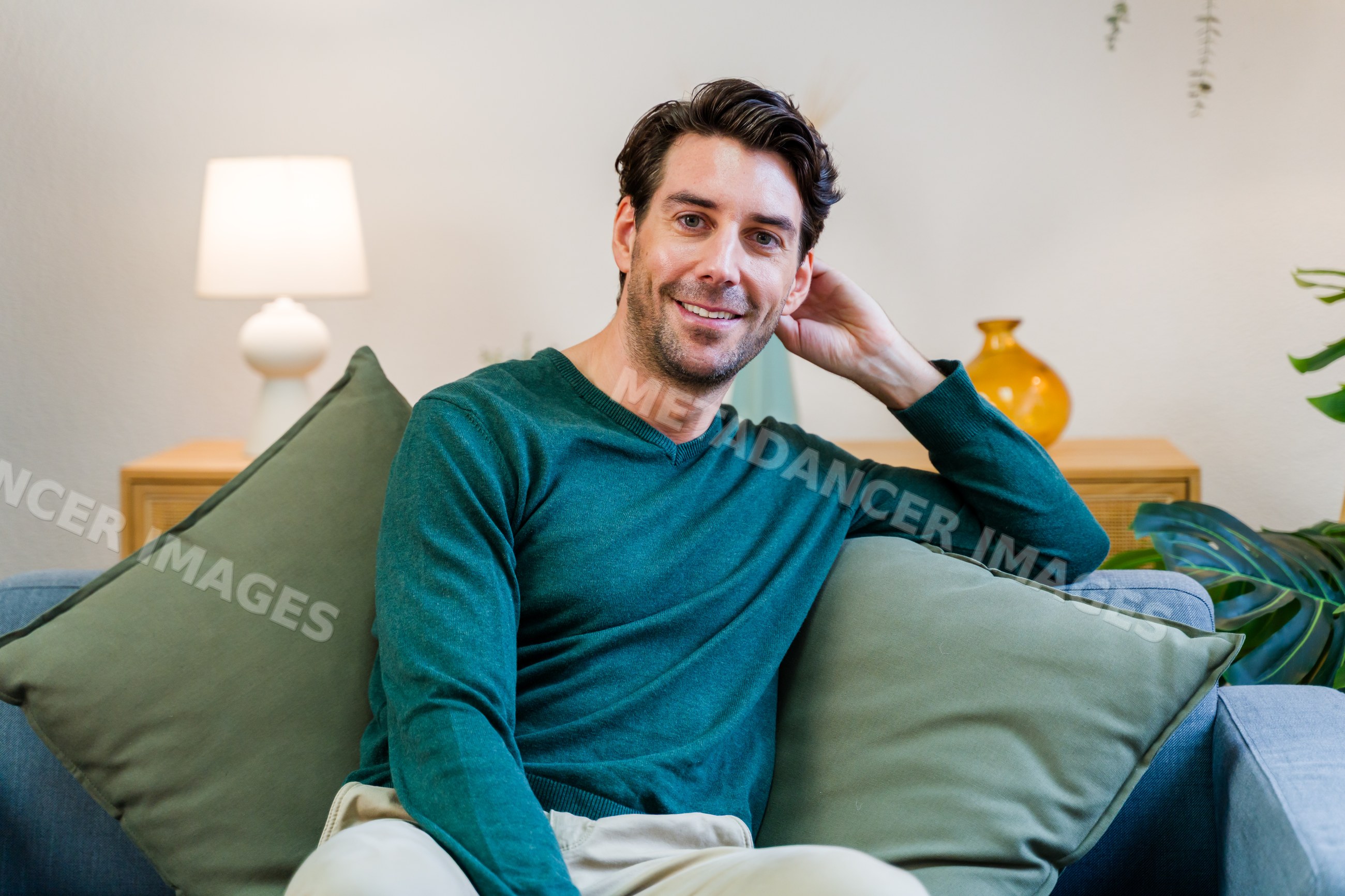 White man sitting on sofa smiling