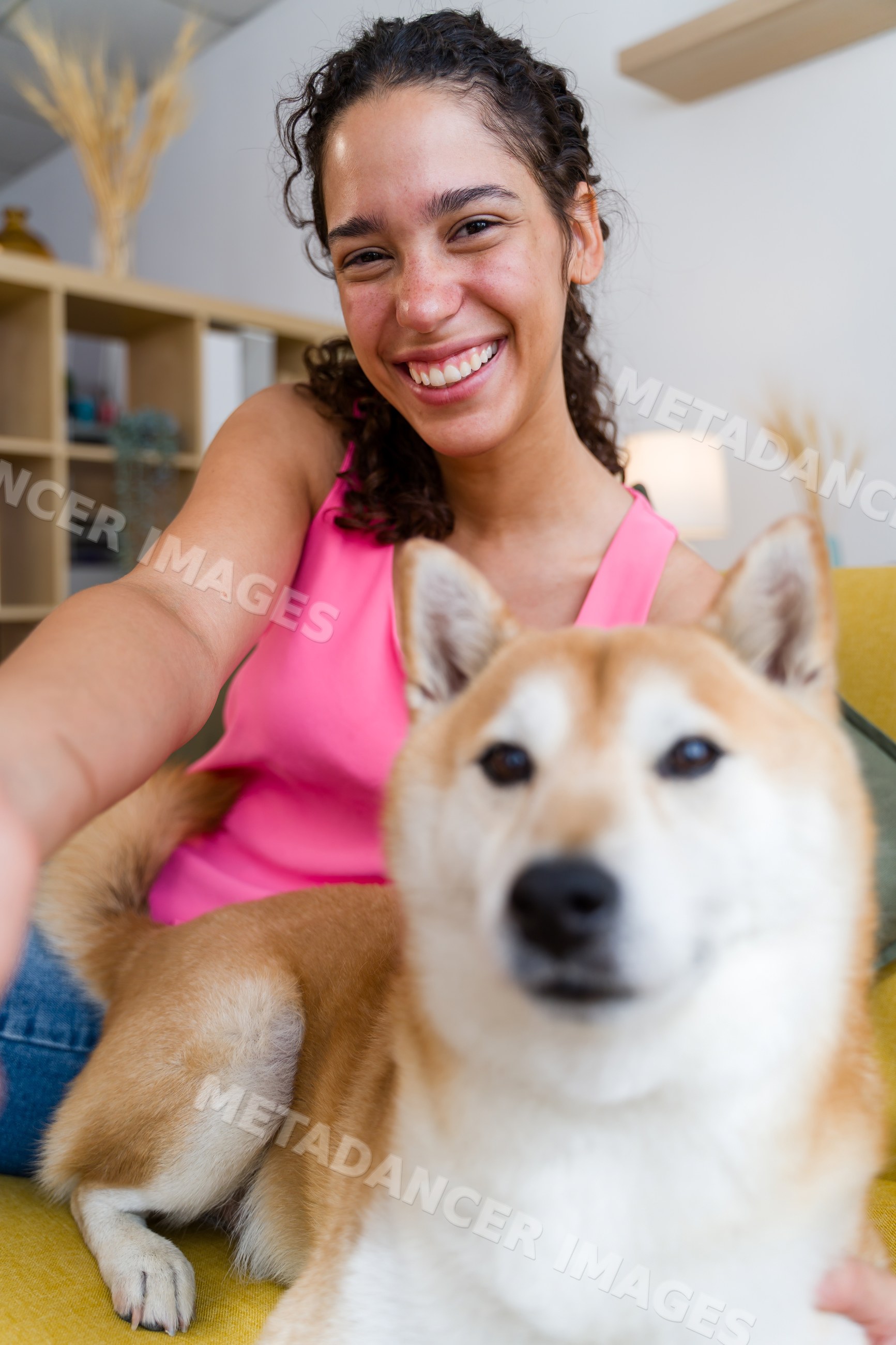 A Hispanic woman happily takes a selfie with her small dog