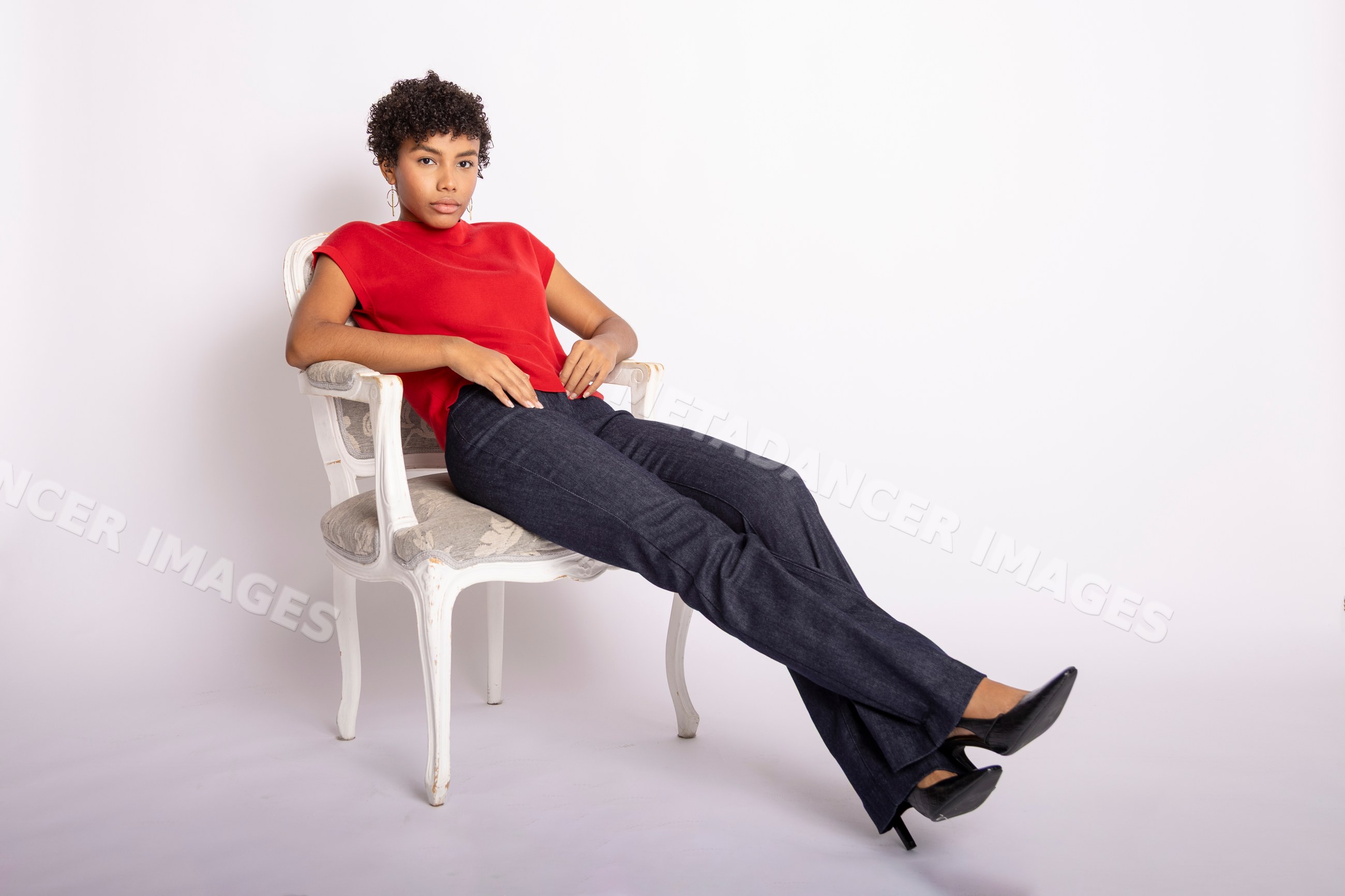 Hispanic woman in red top and black fitted pants sitting on vintage