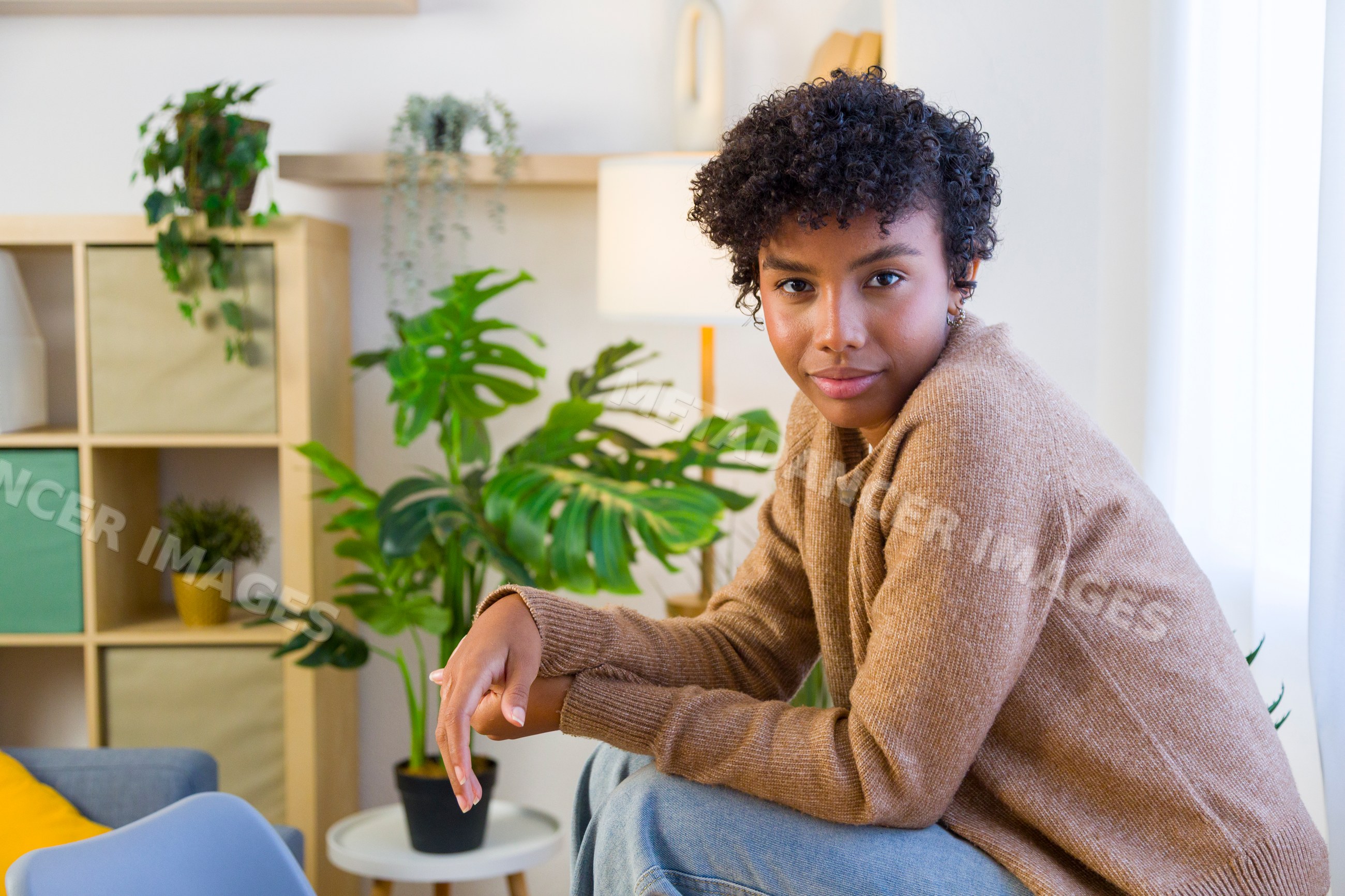 Young African American woman seated in cozy home interior with plants