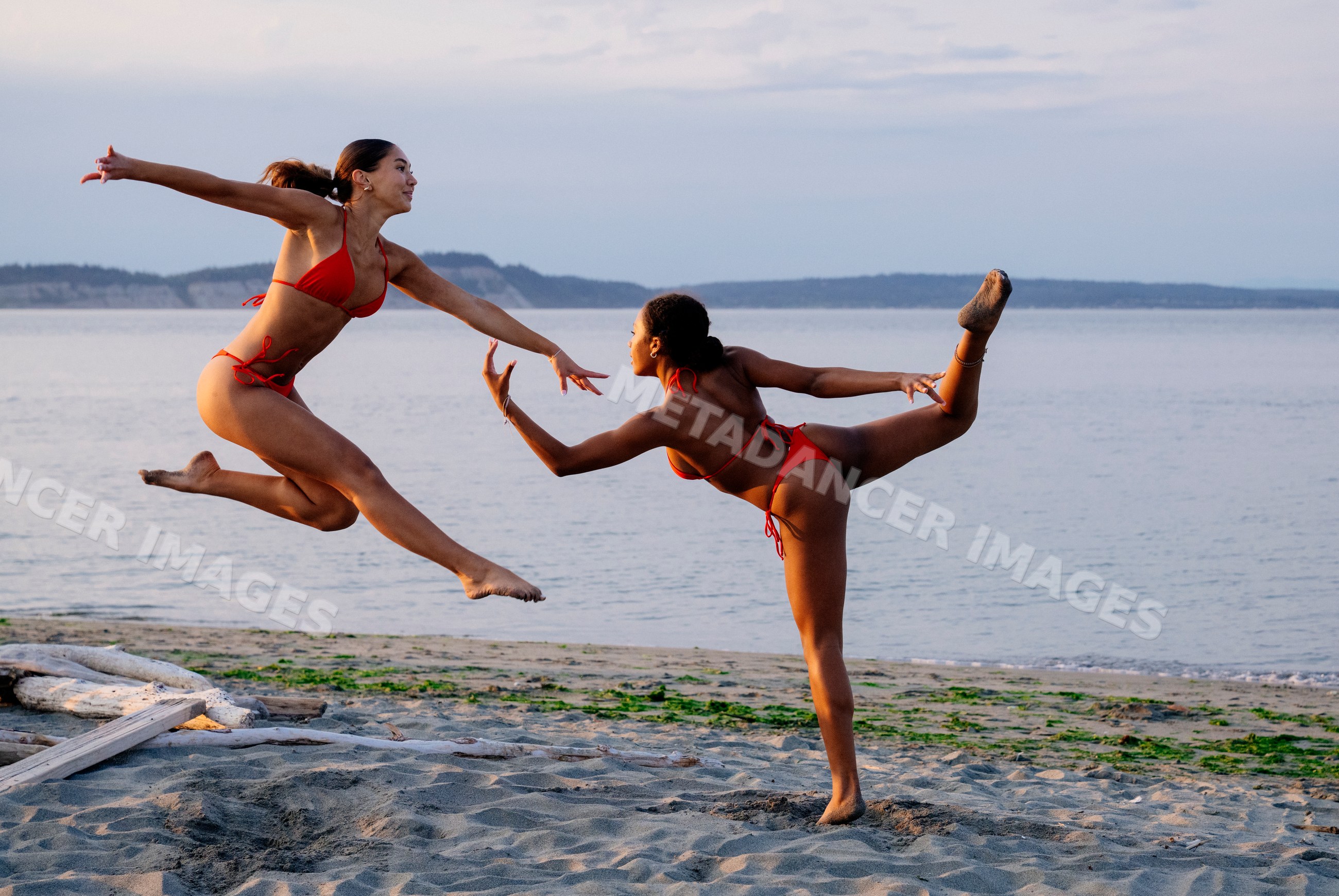 Two women practicing partner acrobatics yoga on a beach in wa USA