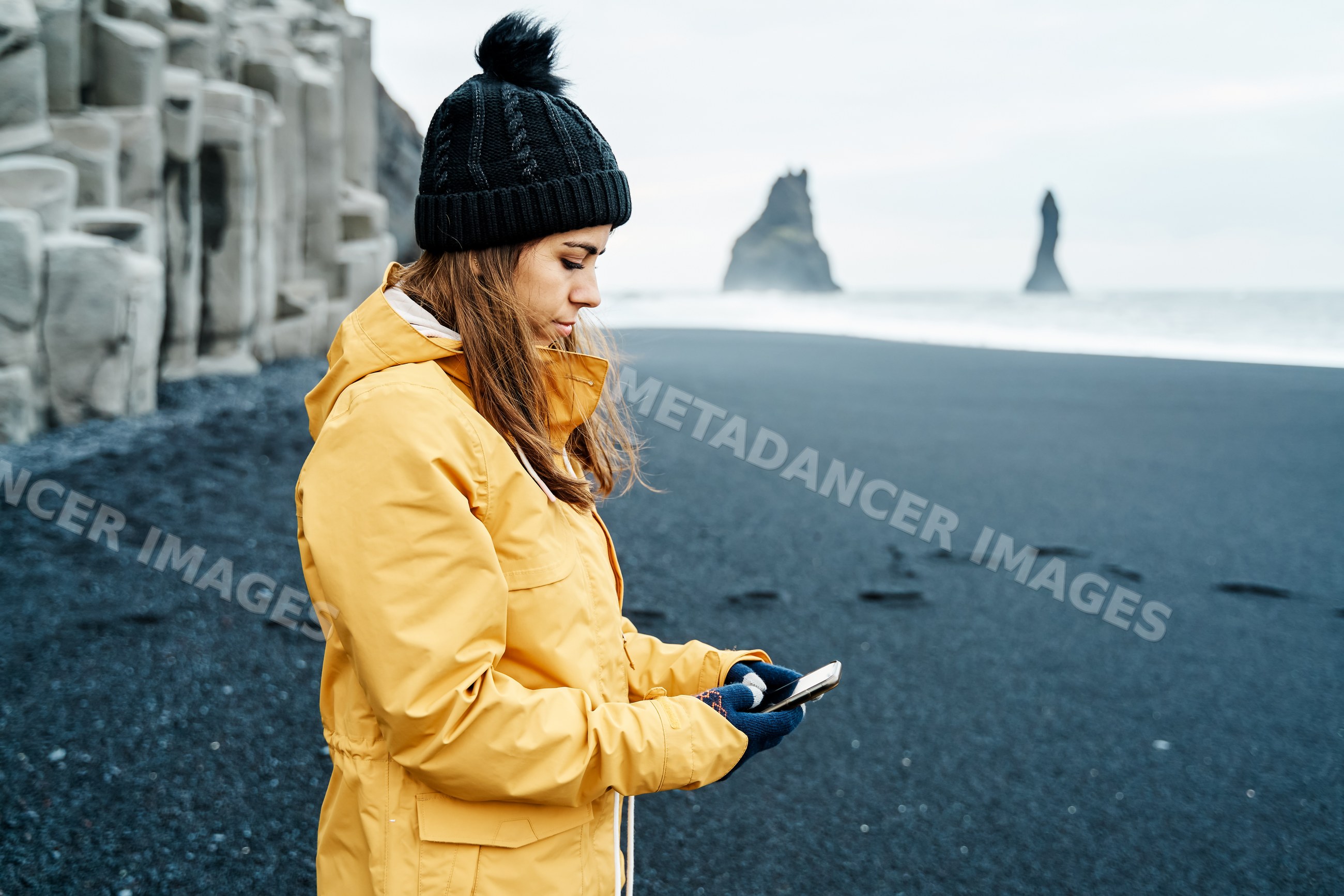 White Woman using smartphone on black sand beach in a beach